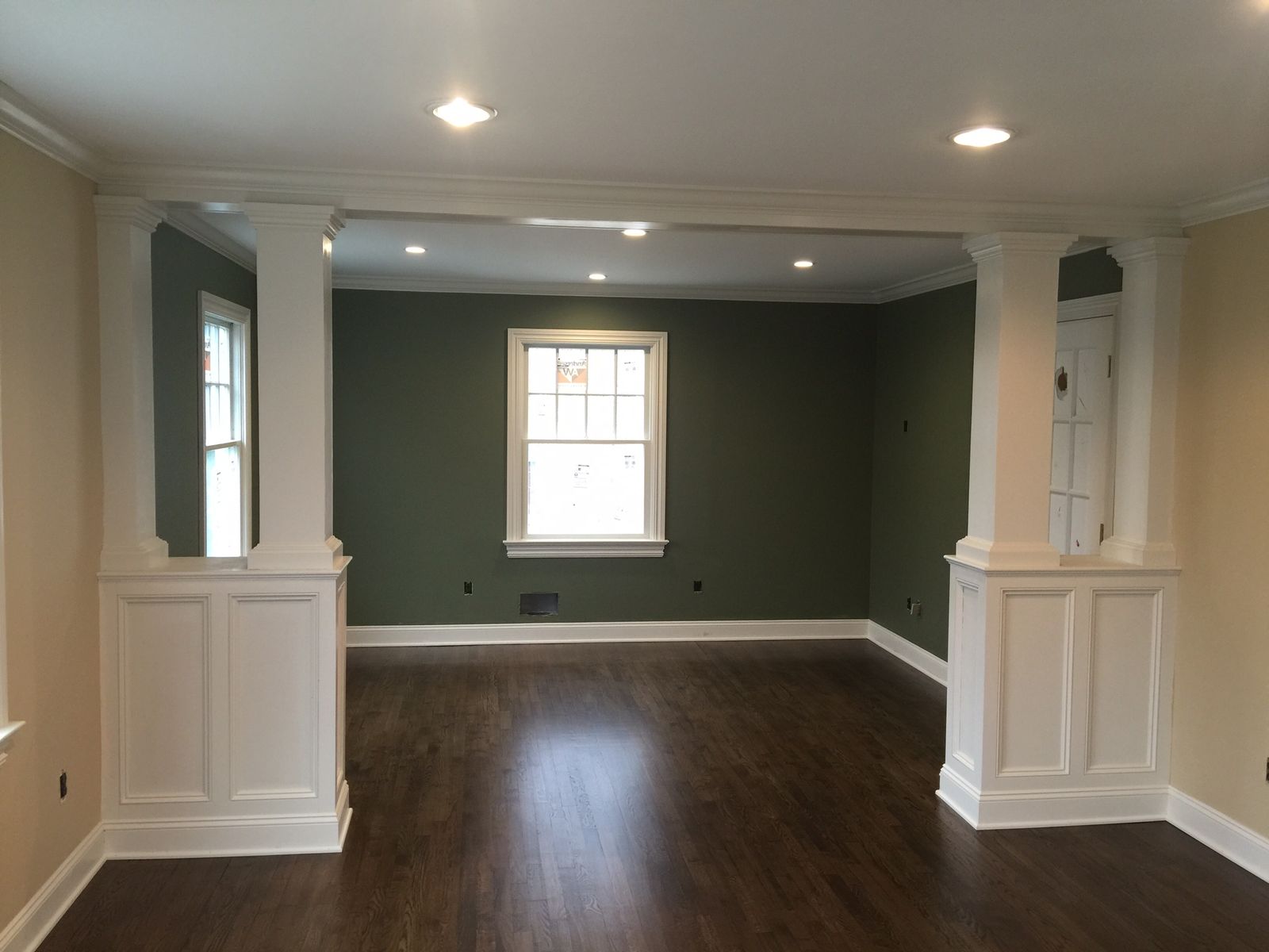 Living room opening with paneled half-wall columns, crown molding and window trim by DMM Carpentry