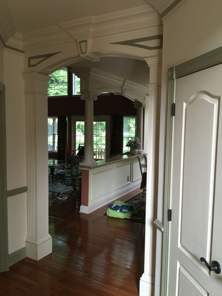 Arched opening with fluted pilasters, columns and a wainscoted half wall, seen past a white interior door