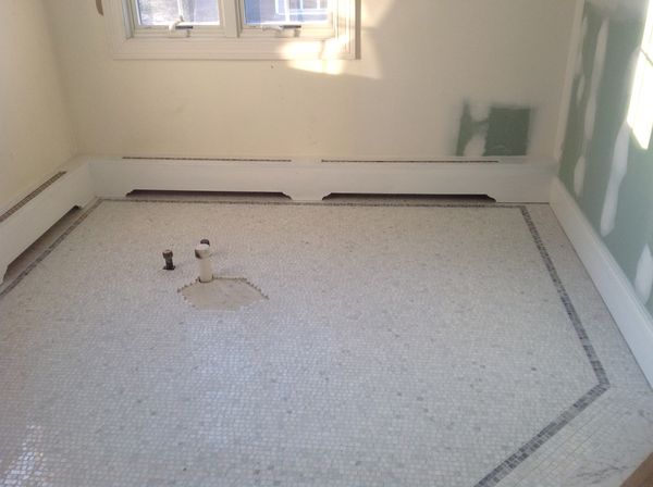 Work in progress: new white baseboard heater covers around a room with a marble mosaic floor