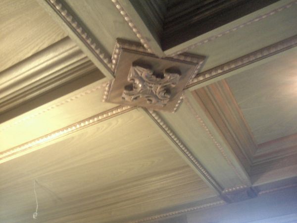 Stained coffered ceiling with bead moulding and a carved medallion where the beams cross