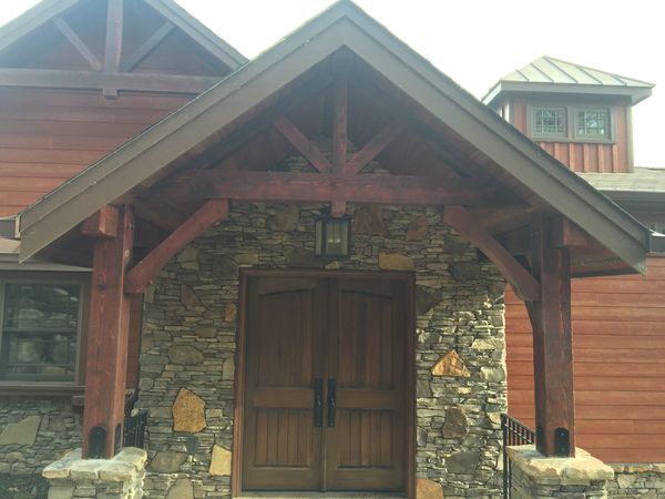 Double wood entry doors in a stone wall under a timber-frame gable porch, installed by David