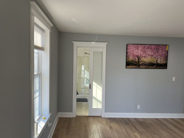 Frosted-glass sliding door to a bathroom with capped head casing, matching window trim and white baseboard, installed by David
