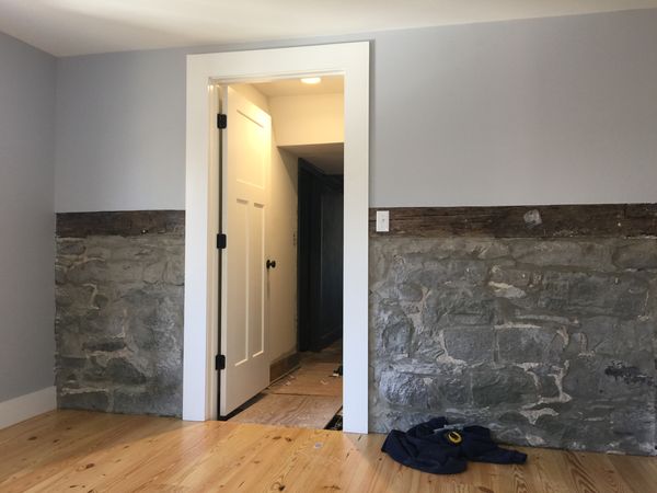 White panel interior door with wide flat casing, set in a room with a stone lower wall and wood floor, installed by David