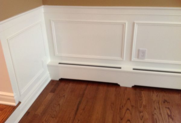 White wainscoting with picture-frame panel moulding and a matching baseboard heater cover above a hardwood floor