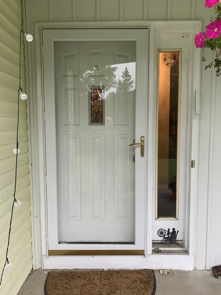White entry door with a sidelight and a glass storm door, seen from the porch, installed by David